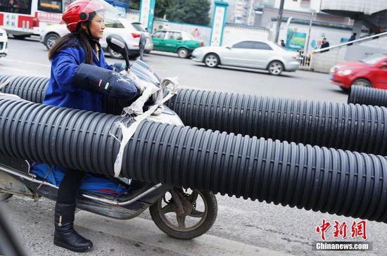 贵阳女子骑摩托车载超长管穿梭车流(图)