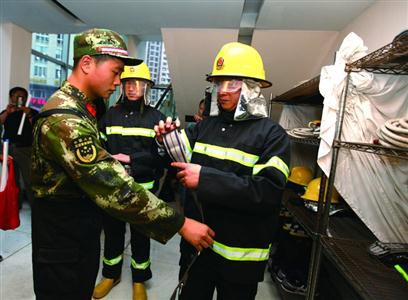 消防战士在辅导消防主管使用微型消防站里的消防器材