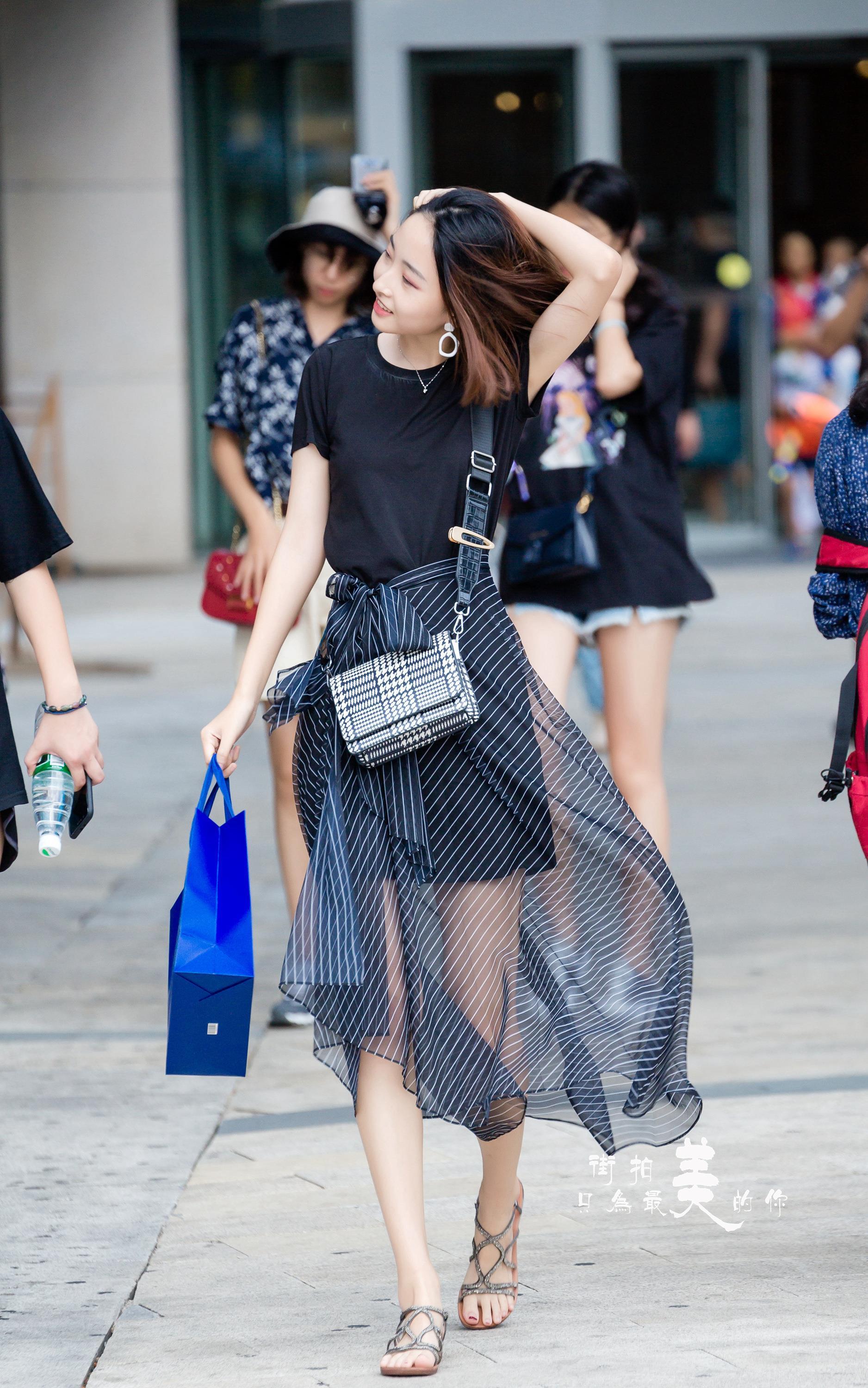购物广场轻撩头发的气质美女 黑色短袖加黑色透视裙,