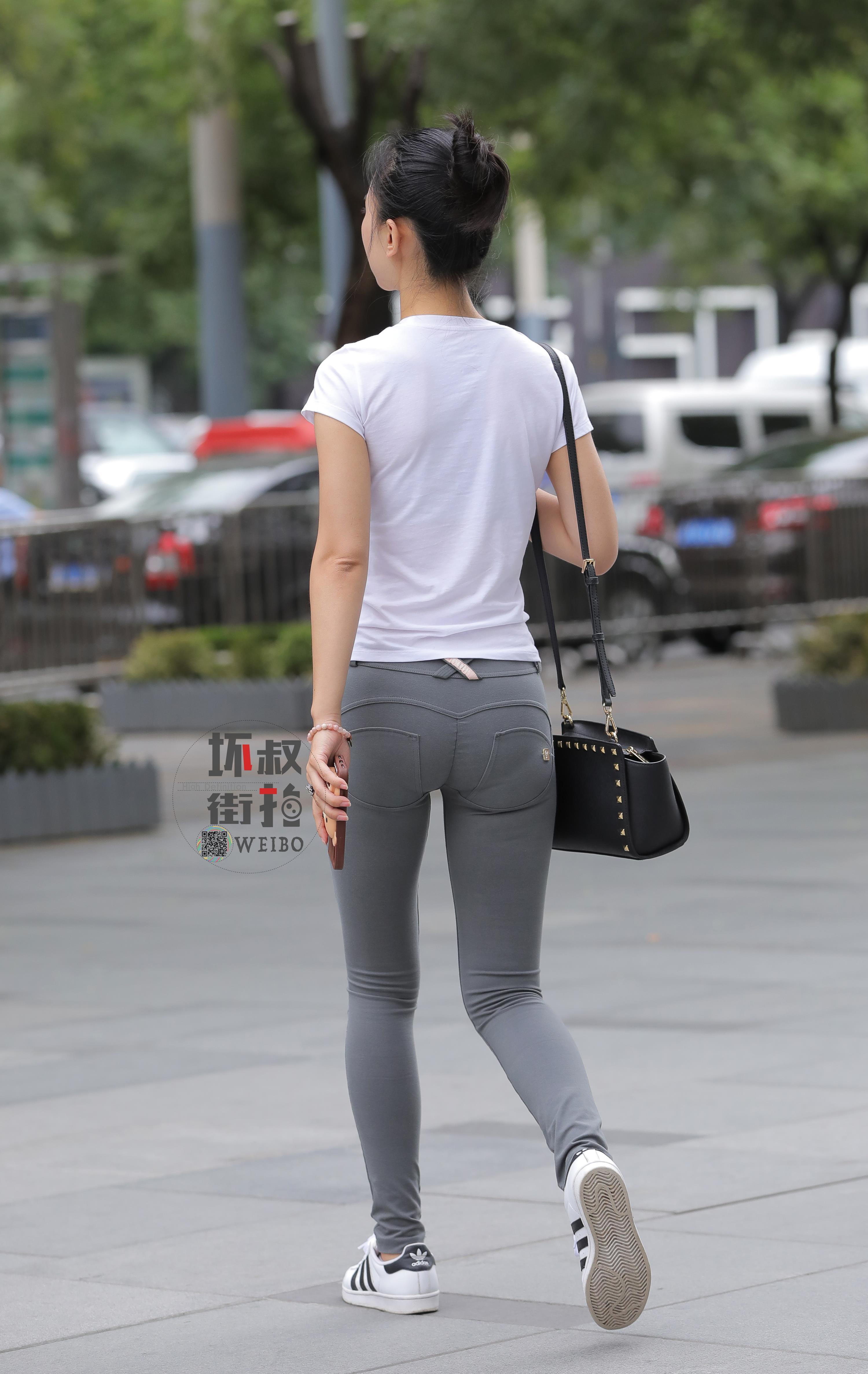 购物街边走边喝奶茶的性感美女 白色短袖加紧身长裤,