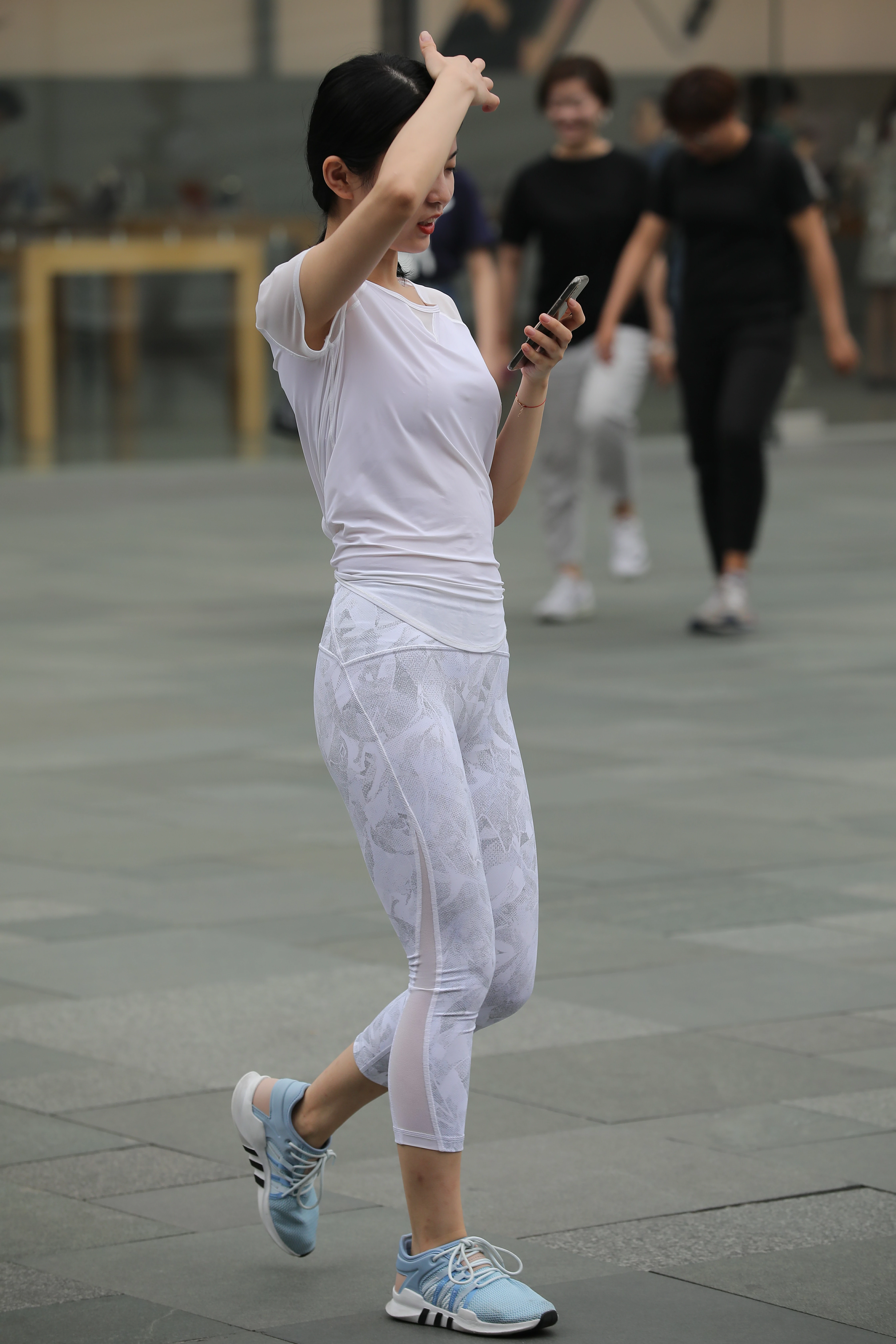 低头玩手机的性感美女白色透视短袖加白色蕾丝紧身裤,