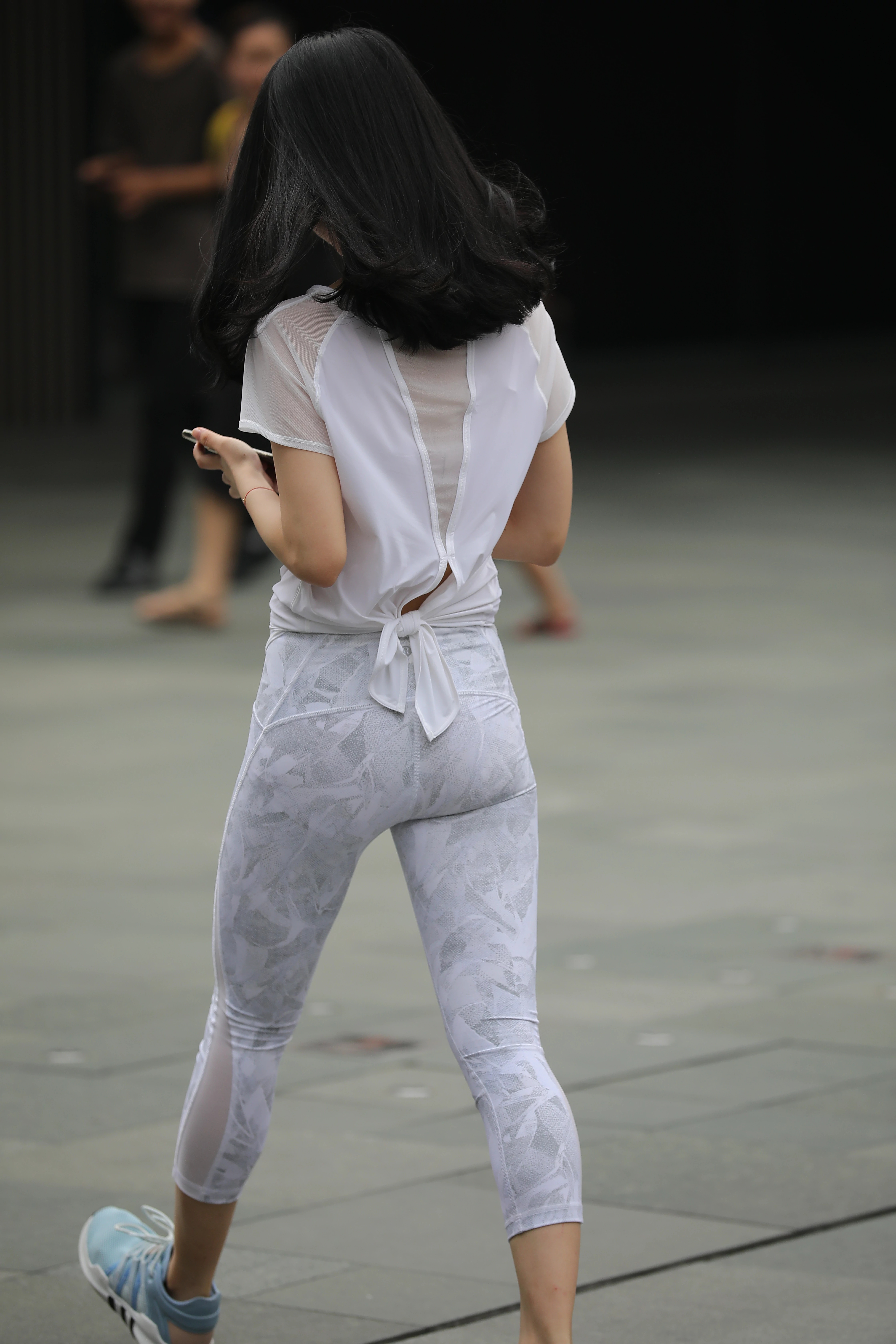 低头玩手机的性感美女白色透视短袖加白色蕾丝紧身裤,